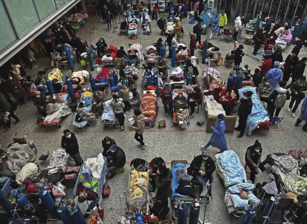 Bệnh nhân trên những chiếc giường được bố trí ở khu vực sảnh trung tâm của một bệnh viện đông đúc được người thân và nhân viên y tế chăm sóc, tại Thượng Hải hôm 13/01/2023. (Ảnh: Kevin Frayer/Getty Images)