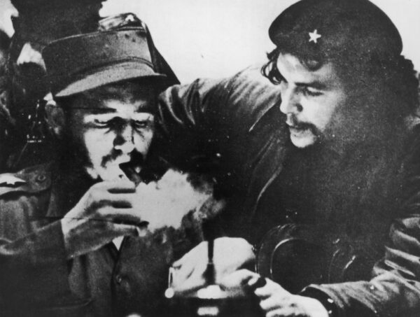 Hình ảnh nhà cách mạng Cuba Fidel Castro (trái) châm một điếu xì gà trong khi nhà cách mạng người Argentina Che Guevara đang chăm chú quan sát, ảnh được chụp trong những ngày đầu của chiến dịch du kích của họ ở dãy núi Sierra Maestra của Cuba, khoảng năm 1956. (Ảnh: Hulton Archive/Getty Images)
