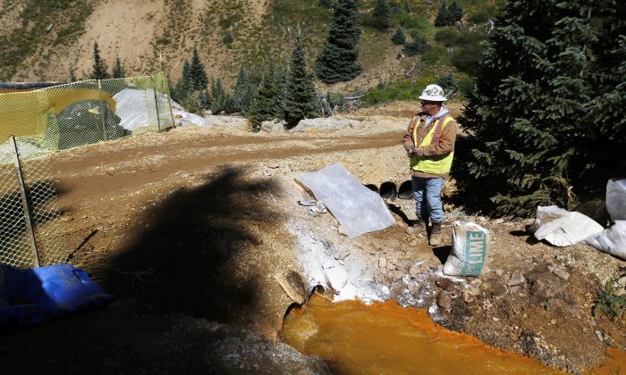 Một nhà thầu của Cơ quan Bảo vệ Môi trường Hoa Kỳ (EPA) giữ sẵn một túi vôi để điều chỉnh độ PH của nước thải từ mỏ chảy vào một loạt các ao giữ trầm tích, một phần của việc giảm thiểu nguy hiểm do hậu quả của vụ nổ tại khu vực mỏ Gold King bên ngoài Silverton, Colorado, năm 2015. (Ảnh: Brennan Linsley/AP Photo)