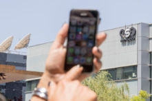 Một phụ nữ Israel sử dụng iPhone của mình trước tòa nhà trụ sở của NSO Group của Israel, ở Herzliya, gần Tel Aviv, Israel, ngày 28/08/2016. (Ảnh: Jack Guez/AFP qua Getty Images)