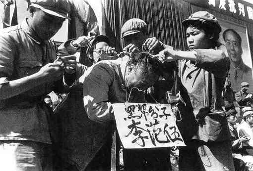 Các cán bộ Đảng Cộng sản treo một tấm bảng trên cổ của một người đàn ông Trung Quốc. Dòng chữ trên tấm bảng ghi tên của người đàn ông này và kết tội ông là thuộc thành phần “Ngũ hắc loại”. (Ảnh: Tài sản công)