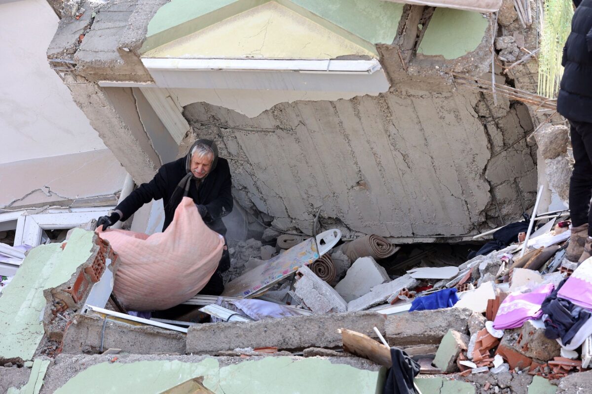 Một người đàn ông dọn chiếc chăn từ dưới đống đổ nát của một tòa nhà bị sập ở Kahramanmaras, Thổ Nhĩ Kỳ, hôm 07/02/2023. (Ảnh: Adem Altan/AFP/Getty Images)