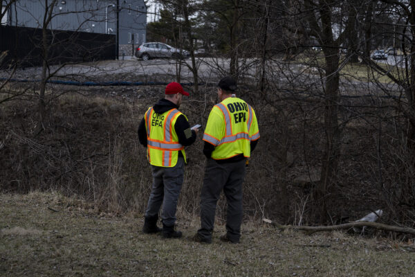 Hai nhân viên trong đội Ứng phó Khẩn cấp của EPA Ohio đứng gần con lạch nhỏ gần hiện trường vụ nổ tại nhà máy kim loại I. Schumann & Co. ở Bedford, Ohio, hôm 20/02/2023. (Ảnh: Michael Swensen/Getty Images)
