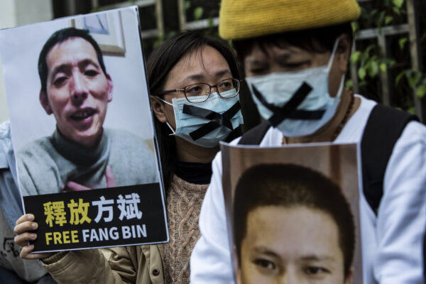 Một nhà hoạt động dân chủ (ở giữa) từ nhóm HK Alliance cầm một tấm bảng ghi tên ký giả công dân bị mất tích Phương Bân khi cô biểu tình bên ngoài văn phòng liên lạc Trung Quốc ở Hồng Kông vào ngày 19/02/2020. (Ảnh: Isaac Lawrence/AFP qua Getty Images)
