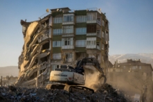 Một chiếc máy xúc làm việc bên cạnh một tòa nhà bị hư hại sau trận động đất gây thương vong ở Kahramanmaras, Thổ Nhĩ Kỳ, hôm 17/02/2023. (Ảnh: Maxim Shemetov/Reuters)