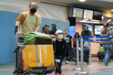 Một người đàn ông và một cậu bé đáp chuyến bay của Cathay Pacific từ Hồng Kông đi cùng nhau tại Phi trường Quốc tế Vancouver, ở Richmond, British Columbia, hôm 04/01/2023. (Ảnh: Darryl Dyck/The Canadian Press)