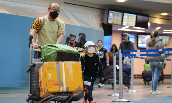 Một người đàn ông và một cậu bé đáp chuyến bay của Cathay Pacific từ Hồng Kông đi cùng nhau tại Phi trường Quốc tế Vancouver, ở Richmond, British Columbia, hôm 04/01/2023. (Ảnh: Darryl Dyck/The Canadian Press)