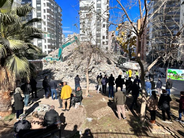 Người dân địa phương đứng xem cần cẩu hoạt động tại đống đổ nát của một tòa nhà tám tầng bị sập sau trận động đất thứ hai trong hai trận động đất ở tỉnh Adana, Thổ Nhĩ Kỳ, hôm 06/02/2023. (Ảnh: Ercan Koc cho The Epoch Times)