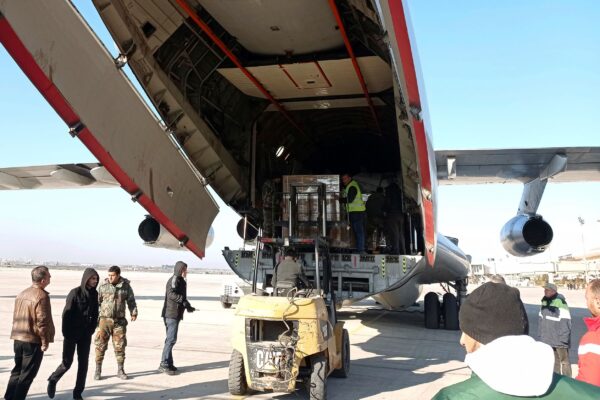 Các nhân viên bốc dỡ hàng viện trợ nhân đạo được gửi từ Saudi Arabia đến Syria sau một trận động đất kinh hoàng, tại phi trường ở Aleppo, Syria, hôm 14/02/2023. (Ảnh: SANA qua AP)