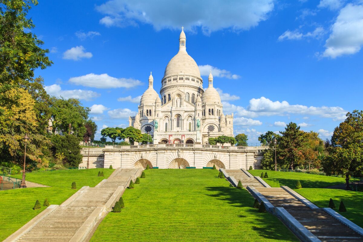 Vương cung thánh đường Sacré-Coeur tọa lạc trên một ngọn đồi cao, dốc của quận Montmartre, trung tâm Paris. Trong bức ảnh là hai cầu thang dẫn vào vương cung thánh đường. Mặt ngoài của tòa kiến trúc này nổi bật với những mái vòm tròn và diện mạo tinh khôi. Phần mặt tiền được xây từ những phiến đá vôi travertine, còn gọi là đá Château-Landon, chất liệu mà khi tiếp xúc với nước sẽ sinh ra khoáng chất calcite, phủ trắng phần mặt tiền một cách tự nhiên. (Ảnh: Marcin Krzyzak/Shutterstock)