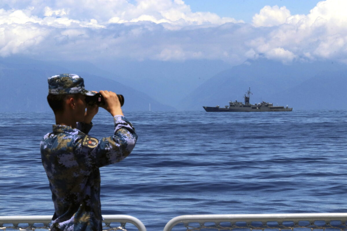 Một thành viên của Quân Giải phóng Nhân dân nhìn qua ống nhòm trong cuộc tập trận quân sự khi khu trục hạm Lan Dương của Đài Loan được nhìn thấy ở hậu cảnh hôm 05/08/2022. (Ảnh: Lin Jian/Tân Hoa Xã qua AP)