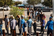Những người nhập cư bất hợp pháp chờ đợi bên ngoài Trung tâm Nguồn lực cho Người nhập cư để nhận thực phẩm từ Tổ chức Từ thiện Công giáo San Antonio ở San Antonio, Texas, hôm 19/09/2022. (Ảnh: Jordan Vonderhaar/Getty Images)