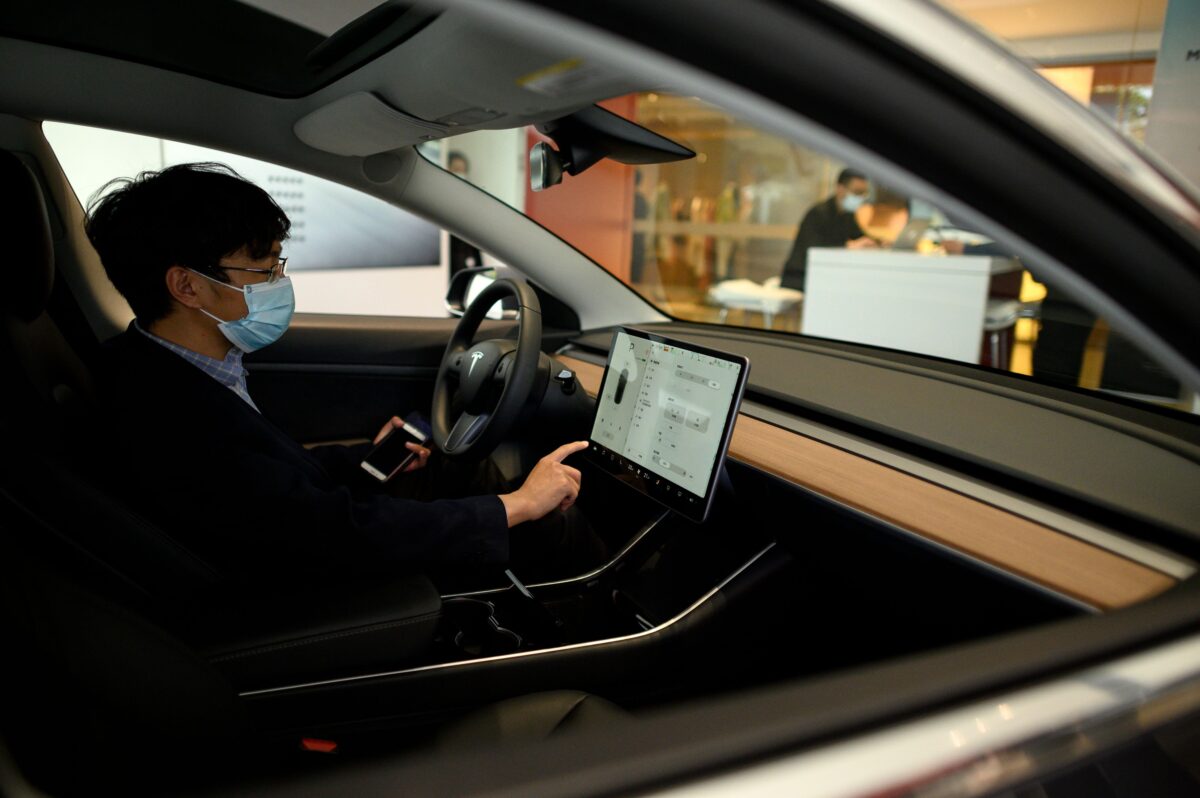 Một khách hàng đang kiểm tra màn hình cảm ứng trên bảng điều khiển của một chiếc xe hơi Tesla được trưng bày tại một phòng trưng bày ở Bắc Kinh vào ngày 10/05/2020. (Ảnh: Noel Celis/AFP/Getty Images)
