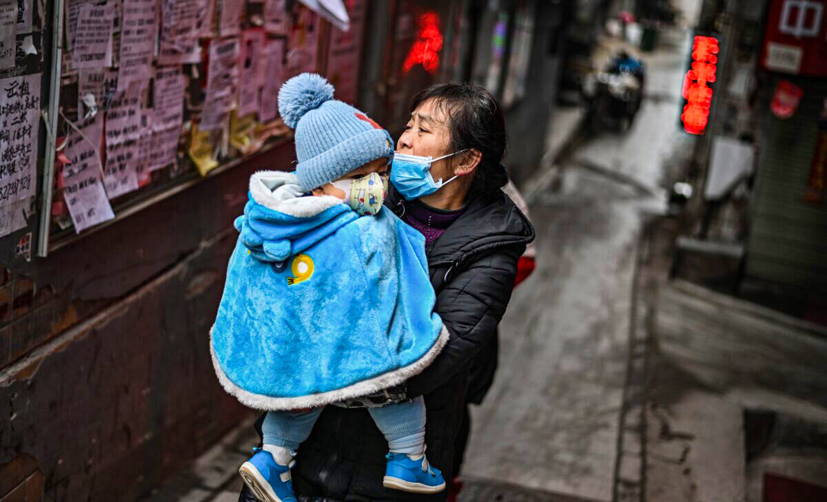 Một người phụ nữ đeo khẩu trang bế con trên tay ở Vũ Hán thuộc tỉnh Hồ Bắc, miền trung Trung Quốc, vào ngày 22/01/2021. (Ảnh: Hector Retamal/AFP qua Getty Images)