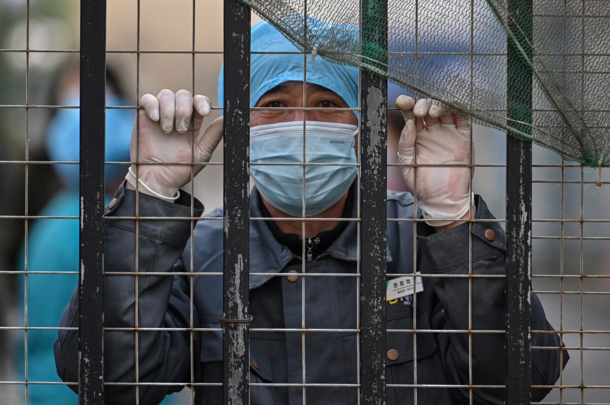 Một nhân viên đeo khẩu trang nhìn ra từ lối vào của bệnh viện về phía Trung tâm Kiểm soát và Phòng ngừa Dịch bệnh Vũ Hán ở Vũ Hán, thuộc tỉnh Hồ Bắc, miền trung Trung Quốc vào ngày 01/02/2021. (Ảnh: Hector Retamal/AFP qua Getty Images)