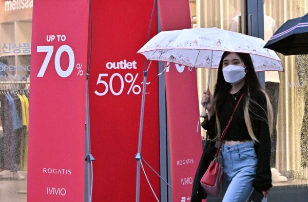 Một người phụ nữ đi ngang qua biển báo giảm giá tại một khu mua sắm ở Seoul vào hôm 13/07/2022, sau khi ngân hàng trung ương Nam Hàn đưa ra mức tăng lãi suất nửa điểm lịch sử để chế ngự lạm phát đang gia tăng nhanh. (Ảnh: Jung Yeon-je/AFP/Getty Images)