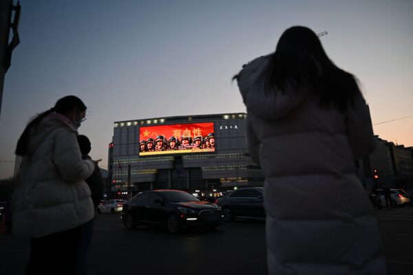 Vài ngày trước khi khai mạc kỳ họp thường niên của Đại hội đại biểu Nhân dân Toàn quốc của Trung Quốc, mọi người chờ đợi để băng qua đường gần một biển quảng cáo tuyên truyền quân sự ở Bắc Kinh hôm 02/03/2023. (Ảnh: Greg Baker/AFP qua Getty Images)