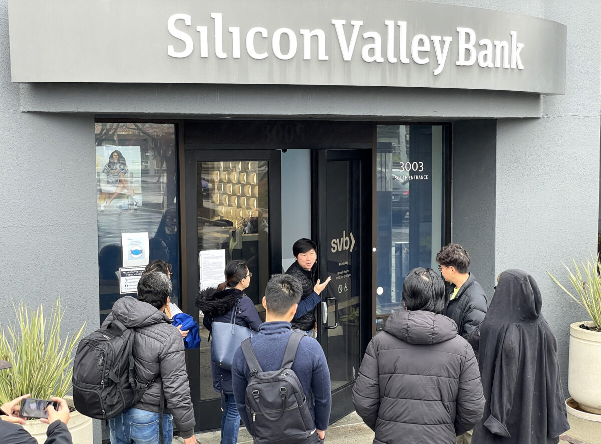Một nhân viên (ở giữa) nói với mọi người rằng trụ sở chính của Silicon Valley Bank (SVB) đã đóng cửa ở Santa Clara, tiểu bang California, hôm 10/03/2023. (Ảnh: Justin Sullivan/Getty Images)