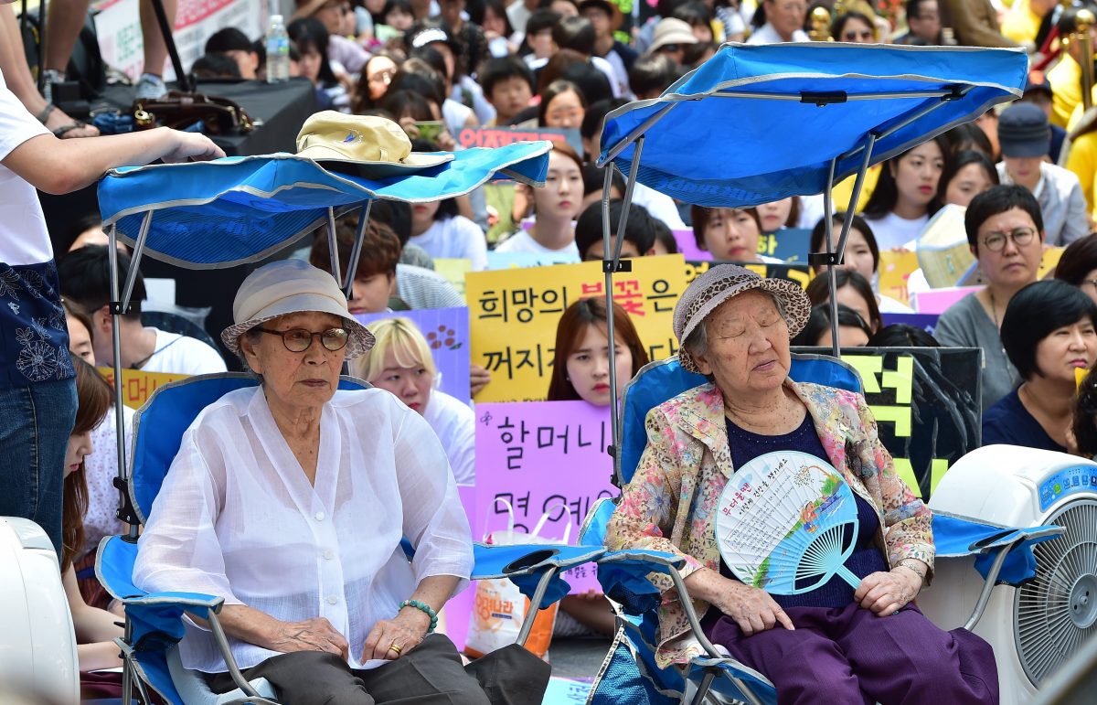 Các cụ bà Nam Hàn từng phải làm “phụ nữ mua vui” Kim Bok-Dong (trái) và Gil Won-Ok (phải), những người bị buộc làm nô lệ tình dục cho quân đội Nhật Bản trong Đệ nhị Thế chiến, tham gia một cuộc biểu tình cùng những người ủng hộ khác để yêu cầu Tokyo xin lỗi vì bắt phụ nữ vào các nhà thổ quân sự trong Đệ nhị Thế chiến bên ngoài Đại sứ quán Nhật Bản ở Seoul vào ngày 12/08/2015. (Ảnh: Jung Yeon-Je/AFP/Getty Images)