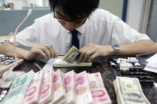 Một nhân viên đếm những chồng nhân dân tệ Trung Quốc và USD tại một ngân hàng ở Thượng Hải, vào ngày 22/07/2005. (Ảnh: China/Getty Images)