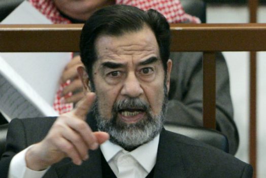 Cựu Tổng thống Iraq Saddam Hussein chỉ tay khi nghe bên công tố trong phiên tòa xét xử tội diệt chủng của ông trong chiến dịch ‘Anfal’ ở Baghdad, Iraq, vào ngày 21/12/2006. (Ảnh: Nikola Solic-Pool/Getty Images)