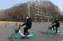 Hai nam sinh đạp xe trong khu đất trống của Đại học Thanh Hoa ở Bắc Kinh vào ngày 28/02/2020. (Ảnh: Greg Baker/AFP qua Getty Images)