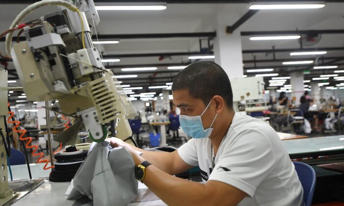 Một công nhân đeo khẩu trang khi làm việc tại nhà máy Maxport, nơi sản xuất quần áo thể thao cho nhiều nhãn hiệu quần áo dệt may, ở Hà Nội, Việt Nam, hôm 21/09/2021. (Ảnh: Nhac Nguyen/AFP/Getty Images)