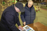 Tổng thống Nga Vladimir Putin (Phải) ra hiệu khi nói chuyện với Phó Thủ tướng Marat Khusnullin khi hai người này xem các hình minh họa về nỗ lực tái thiết trong khi ông đến thăm thành phố Mariupol bị Nga sáp nhập, vào cuối ngày 18/03/2023. (Ảnh: Pool/AFP qua Getty Images)