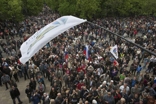 Một nhà hoạt động thân Nga vẫy cờ Cộng hòa Donbas trước đám đông đang ăn mừng việc chiếm được tòa nhà hành chính ở trung tâm Luhansk, Ukraine — một trong những thành phố lớn nhất ở miền đông phức tạp và bất ổn của Ukraine — vào ngày 29/04/2014. (Ảnh: AP Photo/Alexander Zemlianichenko)