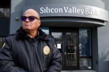 Một nhân viên bảo vệ tại ngân hàng đã phá sản Silicon Valley Bank giám sát một hàng người bên ngoài văn phòng ở Santa Clara, California, hôm 13/03/2023. (Ảnh: Justin Sullivan/Getty Images)
