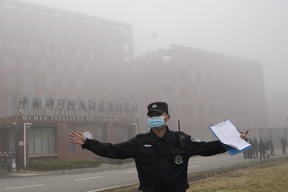 Một nhân viên an ninh di chuyển các ký giả ra khỏi Viện Virus học Vũ Hán sau khi một nhóm của Tổ chức Y tế Thế giới đến thăm thực địa tại Vũ Hán thuộc tỉnh Hồ Bắc của Trung Quốc, Trung Quốc, vào ngày 03/02/2021. (Ảnh: Ng Han Guan/AP Photo)