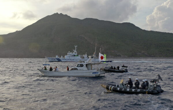 Tàu và thuyền của Lực lượng Tuần duyên Nhật Bản (phía sau và bên phải) đi dọc theo một tàu đánh cá của các nhà hoạt động Nhật Bản (giữa) gần một nhóm đảo tranh chấp mà Trung Quốc gọi là Điếu Ngư và Nhật Bản gọi là Senkaku vào ngày 18/08/2013. (Ảnh: Emily Wang/AP Photo)