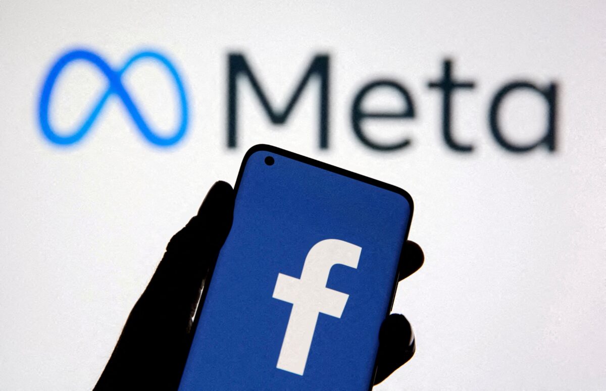 Trong bức ảnh minh họa được chụp vào ngày 28/10/2021 này, một chiếc điện thoại thông minh có logo của Facebook được giơ lên với logo thương hiệu mới Meta ở phía sau. (Ảnh: Dado Ruvic qua Reuters)