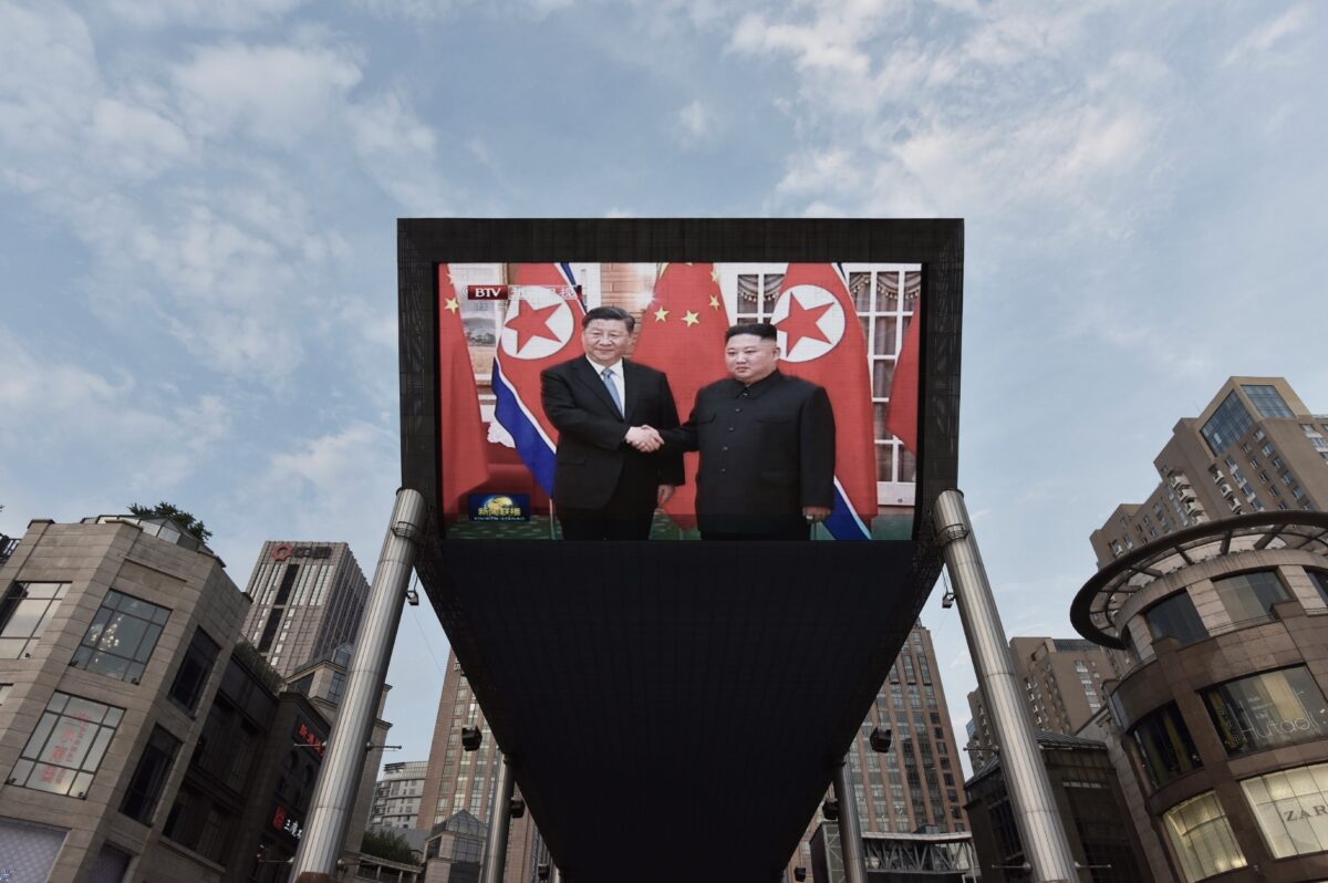 Một màn hình lớn bên ngoài một trung tâm mua sắm ở Bắc Kinh chiếu cảnh lãnh đạo Trung Quốc Tập Cận Bình (Trái) được lãnh đạo Bắc Hàn Kim Jong Un chào đón tại Bình Nhưỡng, vào ngày 20/06/2019. (Ảnh: Greg Baker/AFP)