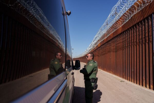 Nhân viên Tuần tra Biên giới Hoa Kỳ Carlos Rivera được phản chiếu trên cửa sổ của một chiếc xe khi anh nói chuyện với một nhân viên khác dọc theo bức tường biên giới ở trung tâm thành phố El Paso, Texas, vào ngày 03/06/2022. (Ảnh: Paul Ratje/AFP qua Getty Images)