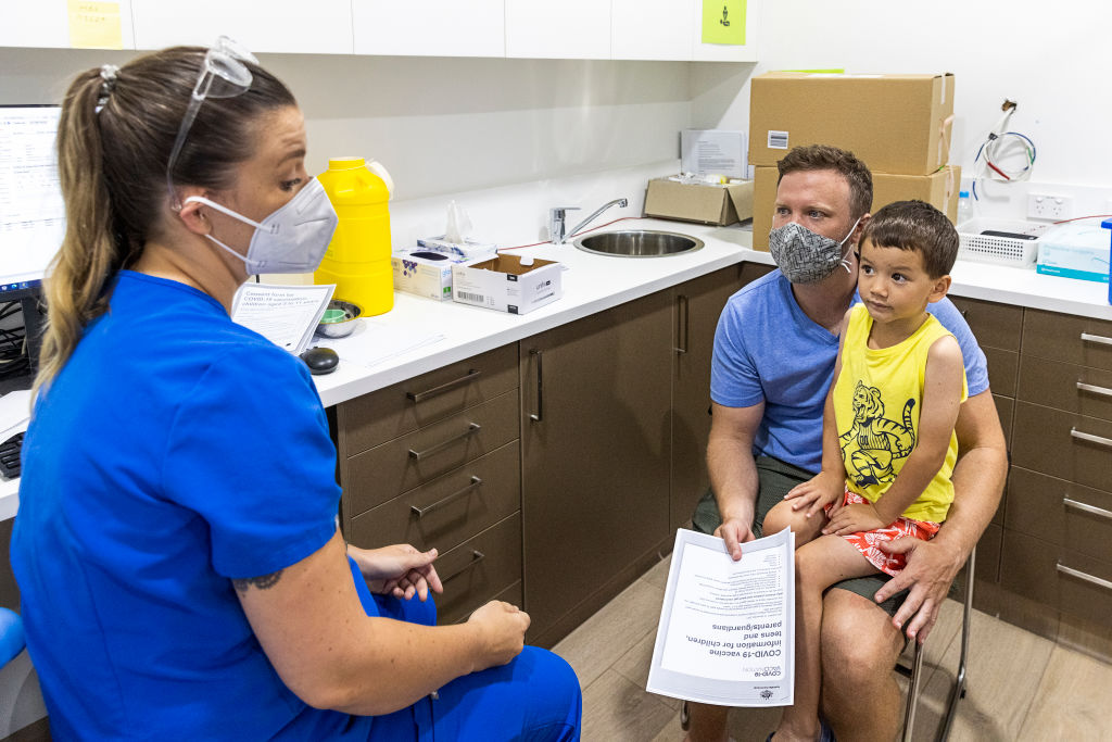 Y tá đã đăng ký Emma Ahearn nói chuyện với ông Stephen Delaney trước khi con trai ông là Lachlan Delany được chích vaccine COVID-19 ở Sydney, Úc, vào ngày 11/01/2022. (Hình ảnh của Jenny Evans/Getty)