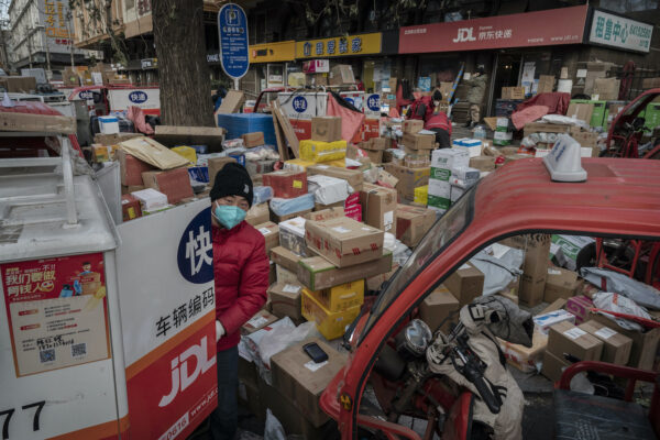 Một tài xế giao hàng sắp xếp các kiện hàng trên đường bên ngoài một kho hàng ở Bắc Kinh, Trung Quốc, vào ngày 21/12/2022. Những kiện hàng này là một phần hàng tồn đọng do đại dịch COVID-19 bùng phát. (Ảnh: Kevin Frayer/Getty Images)