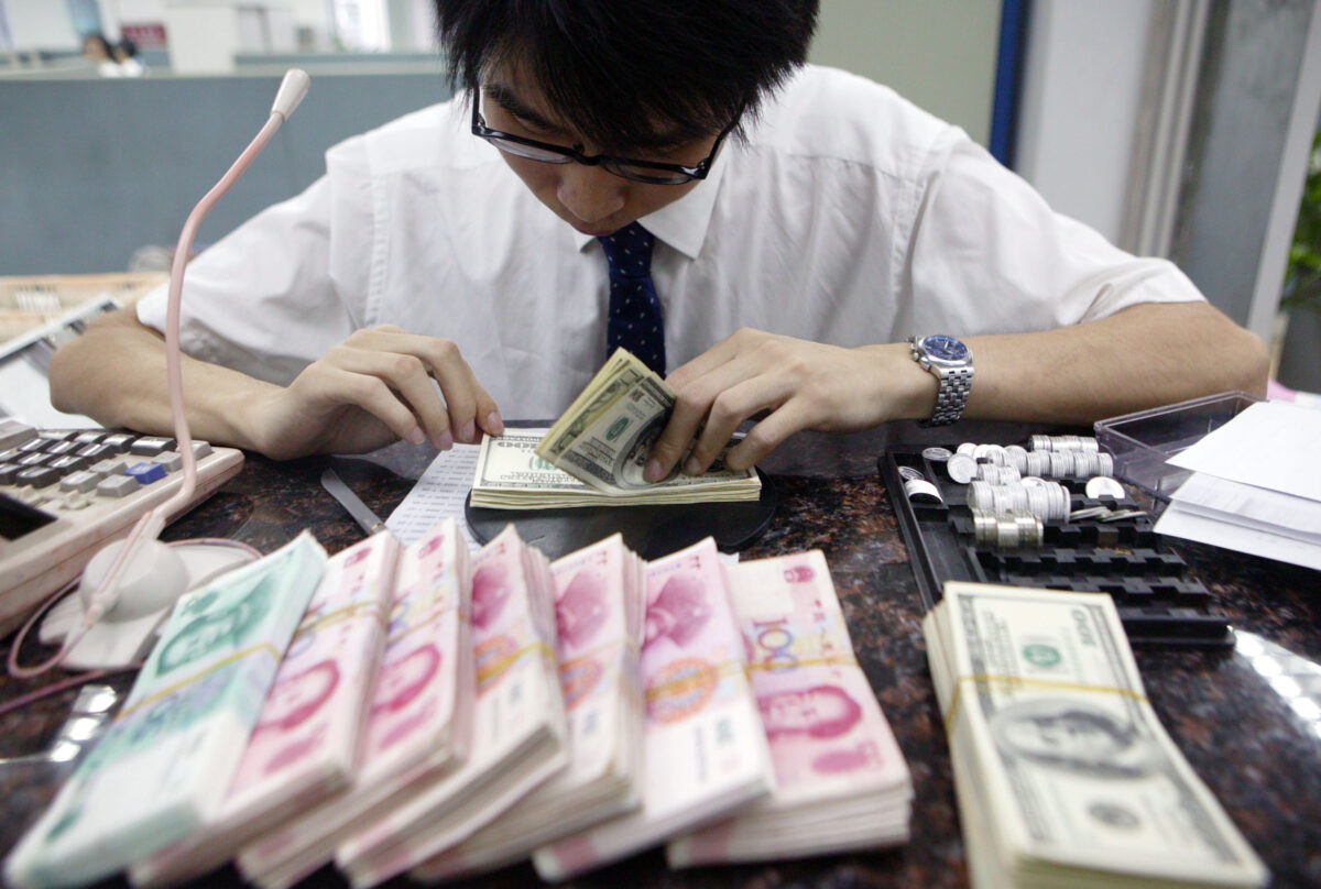 Một nhân viên đếm những tập tiền nhân dân tệ Trung Quốc và USD tại một ngân hàng ở Thượng Hải, Trung Quốc, hôm 22/07/2005. (Ảnh: China Photos/Getty Images)