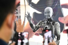 Những người tham dự chụp hình và tương tác với robot hình người có trí thông minh nhân tạo Engineered Arts Ameca khi robot này được đưa ra trình diễn trong Triển lãm Điện tử Tiêu dùng (CES) ở Las Vegas, Nevada, hôm 05/01/2022. (Ảnh: Patrick T. Fallon/AFP qua Getty Images)