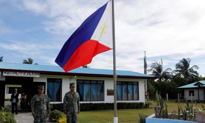 Các binh sĩ Philippines đứng trước một lá quốc kỳ Philippines tại đảo Thị Tứ (Thitu Island) ở vùng Biển Đông đang tranh chấp vào ngày 21/04/2017. (Ảnh: Erik De Castro/Reuters)