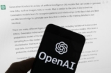 Logo OpenAI trên một chiếc điện thoại di động phía trước màn hình máy điện toán hiển thị câu trả lời từ ChatGPT ở Boston hôm 21/03/2023. (Ảnh: Michael Dwyer/AP Photo)