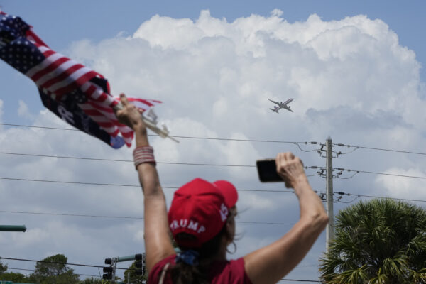 Một người ủng hộ cựu Tổng thống Donald Trump vẫy tay khi phi cơ của ông cất cánh từ Phi trường Quốc tế Palm Beach ở West Palm Beach, Florida, hôm 03/04/2023. (Ảnh: Wilfredo Lee/AP Photo)