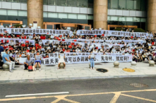 Người dân cầm biểu ngữ và hô vang khẩu hiệu trong một cuộc biểu tình ở lối vào một chi nhánh của ngân hàng trung ương Trung Quốc tại Trịnh Châu, tỉnh Hà Nam, miền trung Trung Quốc, hôm 10/07/2022. (Ảnh: Yang/AP Photo)