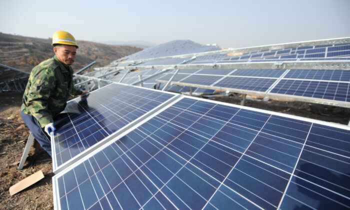 Một công nhân đang lắp đặt các tấm pin mặt trời silicon đa tinh thể khi một dự án  quang năng trên mặt đất, khởi công ở thị trấn Quan Thủy thuộc quận Mưu Bình vào ngày 17/11/2015, ở Yên Đài, tỉnh Sơn Đông, Trung Quốc. (Ảnh: VCG/VCG/Getty Images)