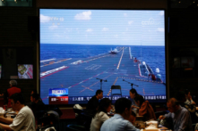 Khách hàng dùng bữa gần một màn hình lớn đang phát đoạn phim đưa tin về các phi cơ thuộc Bộ Tư lệnh Chiến khu Đông bộ của Quân Giải phóng Nhân dân Trung Quốc (PLA) tham gia tuần tra sẵn sàng chiến đấu và các cuộc tập trận “Joint Sword” (Liên Hợp Lợi Kiếm) quanh Đài Loan, tại một nhà hàng ở Bắc Kinh, Trung Quốc, hôm 10/04/2023. (Ảnh: Tingshu Wang/Reuters)