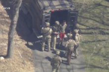 Jack Teixeira, mặc áo phông và quần đùi, đang bị các đặc vụ chiến thuật có vũ trang bắt giữ ở Dighton, Massachusetts, hôm 13/04/2023. (Ảnh: WCVB-TV qua AP)