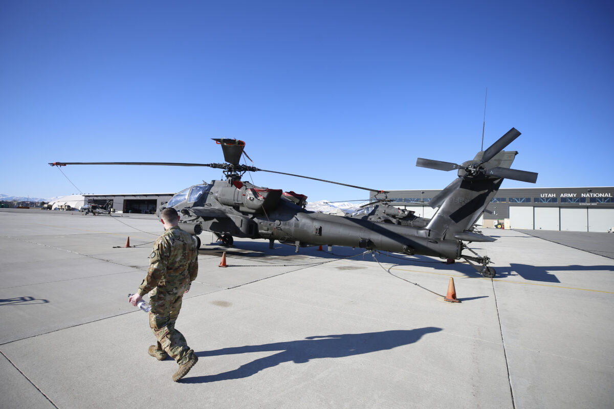 Một nhân viên bảo trì đi ngang qua một chiếc trực thăng AH-64 Apache ở Kearns, Utah, ngày 04/03/2020. (George Frey/Getty Images)
