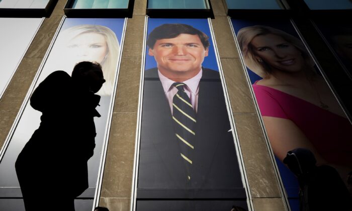 Mọi người đi ngang qua một bảng quảng cáo của người chủ trì chương trình Fox News Tucker Carlson trên tòa nhà News Corporation ở New York vào ngày 13/03/2019. (Ảnh: Brendan McDermid/Reuters)