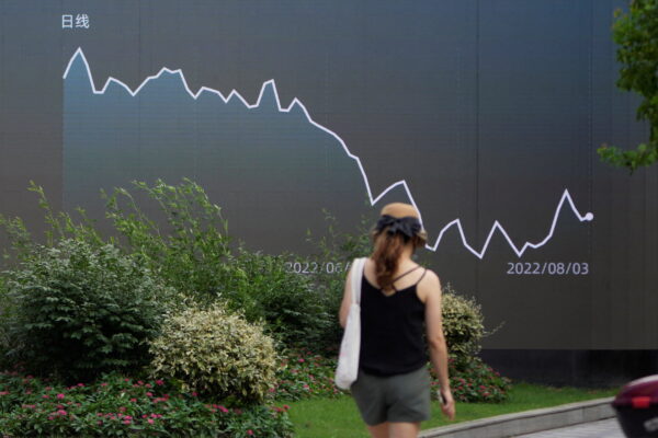 Một khách bộ hành đi ngang qua màn hình lớn hiển thị biểu đồ giao dịch chứng khoán ở Thượng Hải, Trung Quốc, ngày 03/08/2022. (Ảnh: Aly Song/Reuters)