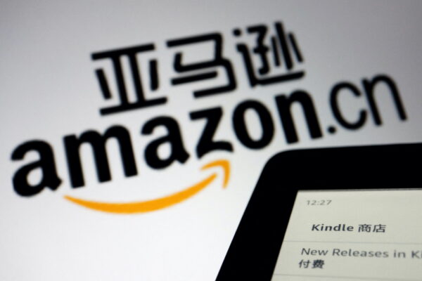 Trong hình minh họa được chụp hôm 15/12/2021 này, biển hiệu của trang web thương mại điện tử Amazon Trung Quốc được đặt cạnh một máy đọc sách điện tử Kindle. (Ảnh: Florence Lo/Reuters)